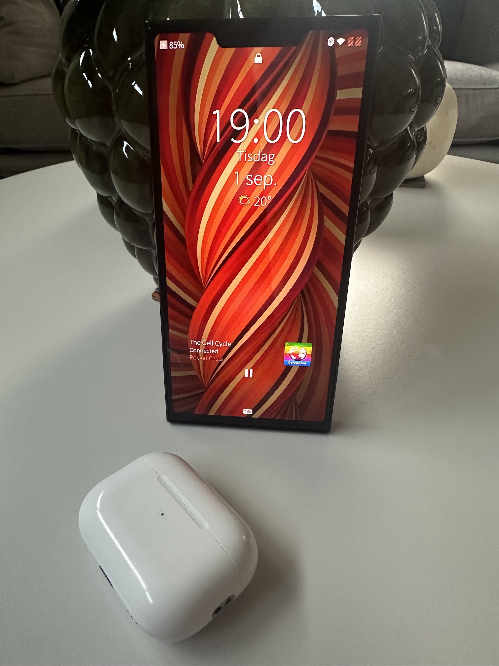 Jolla phone standing on a table, showing the lock screen where Pocket casts is shown playing the podcast Connected
